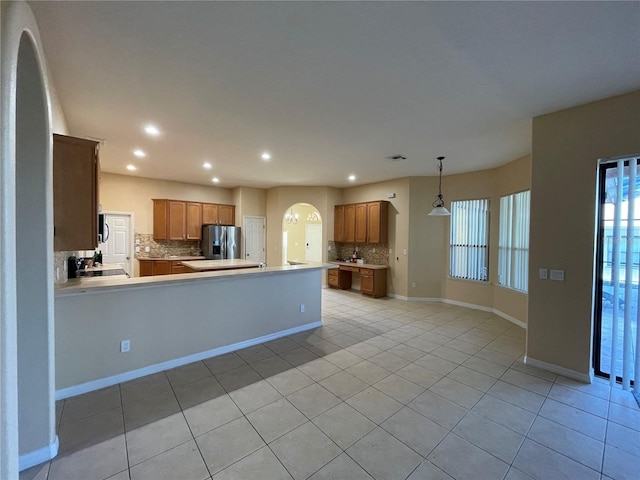 kitchen featuring stainless steel refrigerator with ice dispenser, light tile patterned flooring, decorative backsplash, and kitchen peninsula