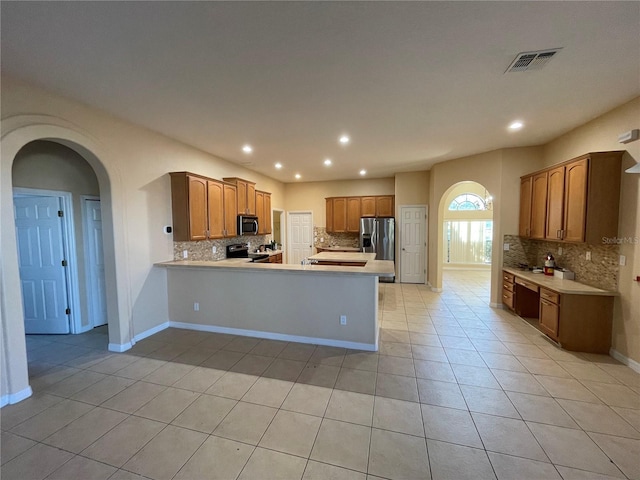 kitchen featuring appliances with stainless steel finishes, kitchen peninsula, light tile patterned flooring, and tasteful backsplash