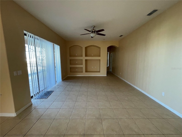 unfurnished living room featuring ceiling fan, built in features, and light tile patterned floors