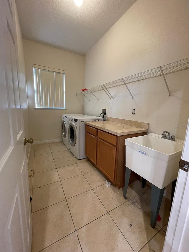 laundry room with washer and dryer, cabinets, light tile patterned flooring, and a textured ceiling