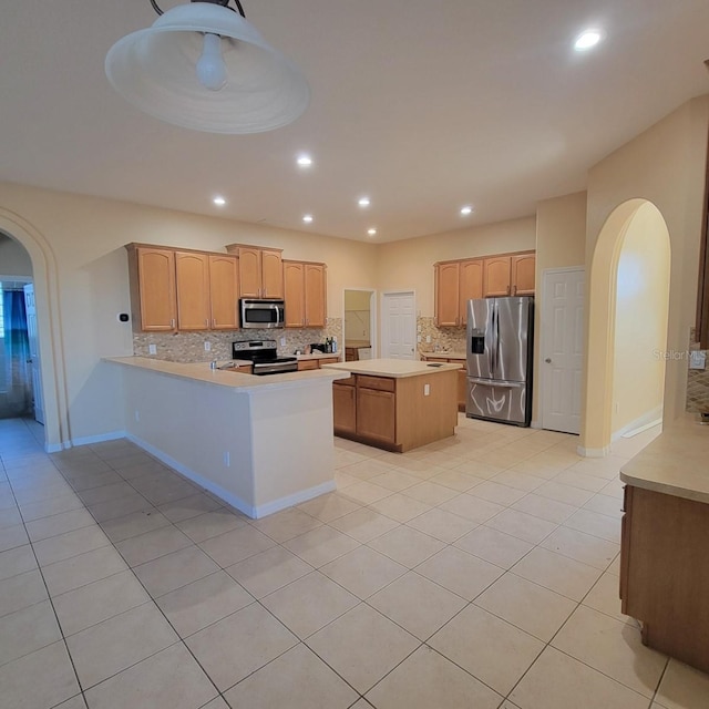 kitchen featuring stainless steel appliances, kitchen peninsula, a kitchen island, and light tile patterned floors