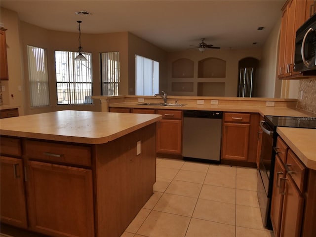 kitchen with stainless steel appliances, an island with sink, light tile patterned floors, sink, and decorative light fixtures