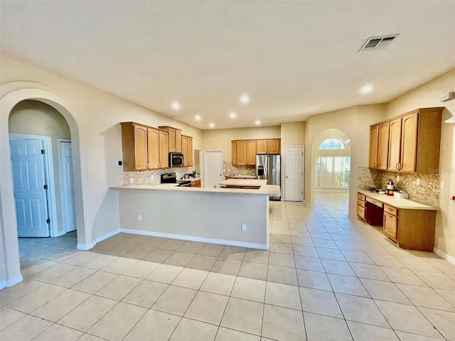 kitchen with visible vents, decorative backsplash, a peninsula, light countertops, and appliances with stainless steel finishes
