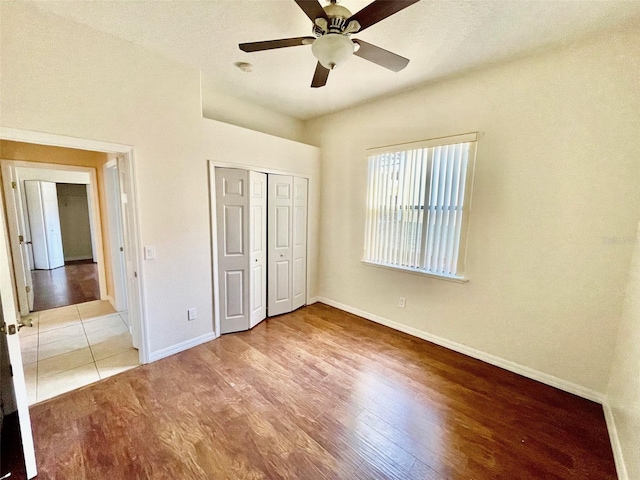 unfurnished bedroom with baseboards, ceiling fan, wood finished floors, and a closet