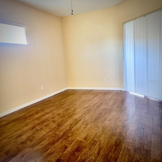 spare room with baseboards and wood finished floors