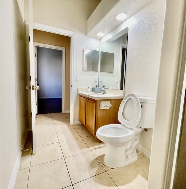 bathroom with vanity, baseboards, tile patterned floors, and toilet