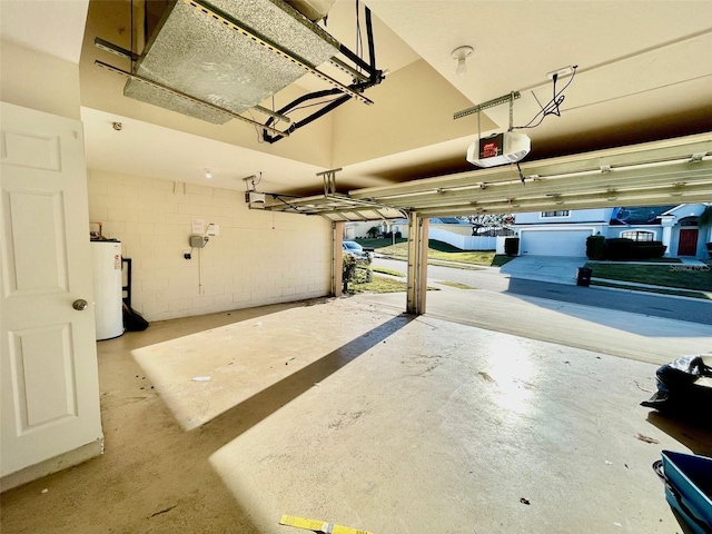 garage with concrete block wall, a garage door opener, and water heater