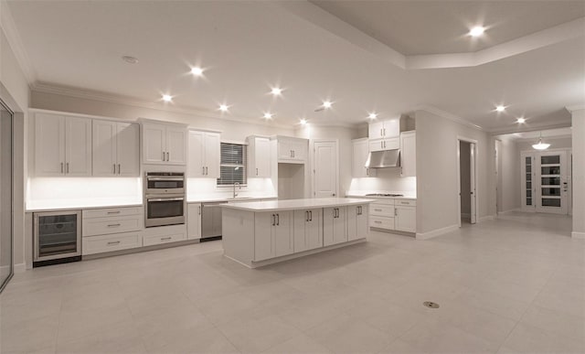 kitchen featuring a center island, white cabinetry, beverage cooler, and sink