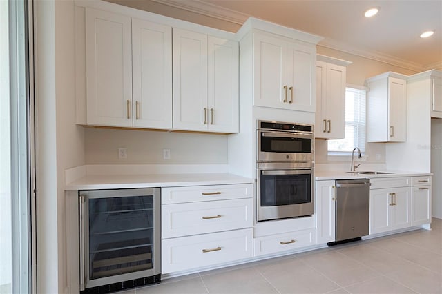 kitchen featuring appliances with stainless steel finishes, white cabinetry, sink, and beverage cooler