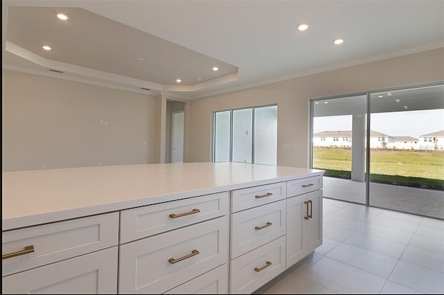 kitchen with a tray ceiling, white cabinets, light tile patterned floors, and ornamental molding