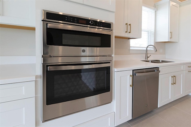 kitchen with white cabinetry, sink, light tile patterned flooring, and appliances with stainless steel finishes