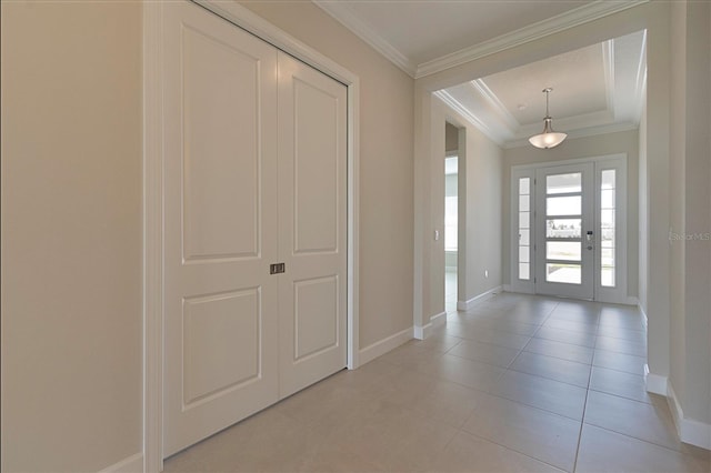 foyer featuring a tray ceiling, crown molding, and light tile patterned flooring