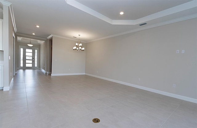 tiled spare room with a chandelier, ornamental molding, and a tray ceiling