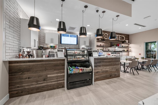 kitchen featuring white cabinets, backsplash, decorative light fixtures, and light hardwood / wood-style floors