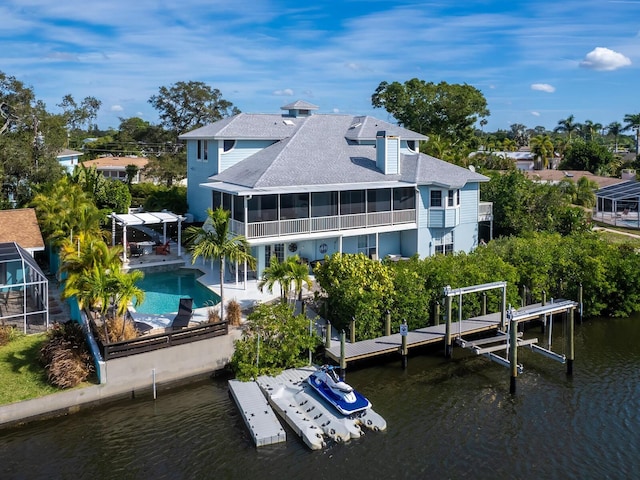 rear view of house with a sunroom, a water view, and a patio