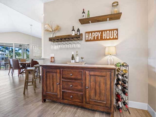 bar featuring vaulted ceiling and light wood-type flooring