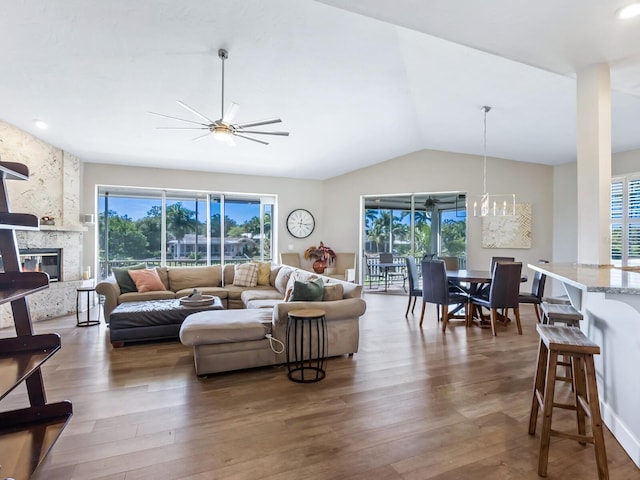 living room with dark hardwood / wood-style floors, ceiling fan with notable chandelier, a high end fireplace, and vaulted ceiling