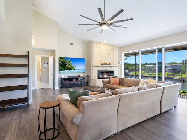 living room with ceiling fan, a large fireplace, dark wood-type flooring, and high vaulted ceiling