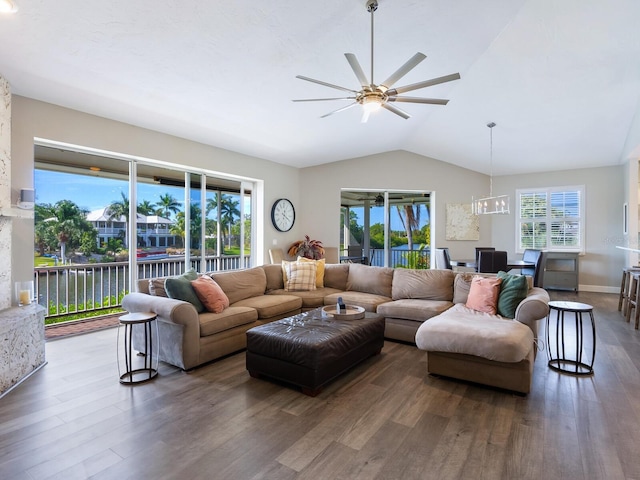 living room featuring ceiling fan with notable chandelier, dark hardwood / wood-style flooring, lofted ceiling, and a water view