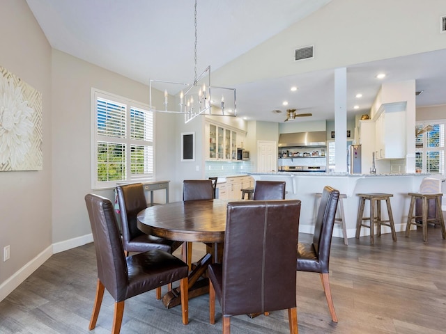 dining space with hardwood / wood-style flooring, a notable chandelier, and lofted ceiling