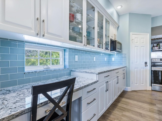 kitchen with decorative backsplash, stainless steel appliances, and white cabinetry