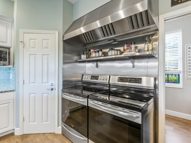 kitchen featuring appliances with stainless steel finishes, light hardwood / wood-style flooring, and white cabinetry