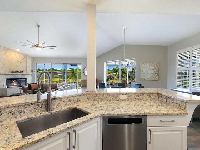 kitchen with white cabinets, a fireplace, vaulted ceiling, sink, and dishwasher