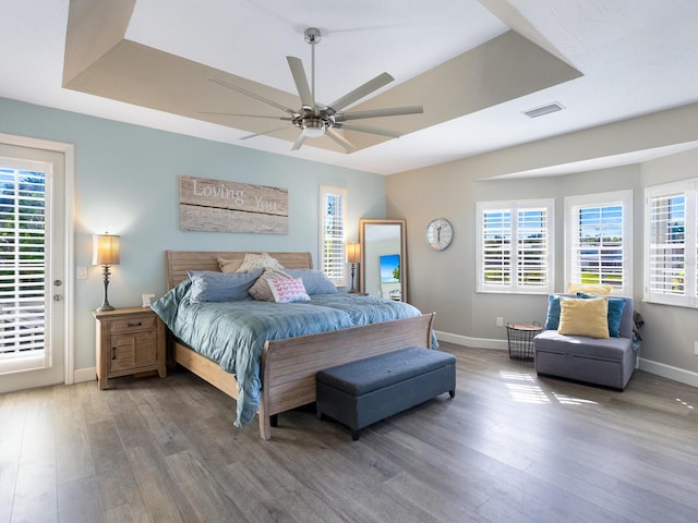 bedroom featuring hardwood / wood-style flooring, ceiling fan, and a raised ceiling