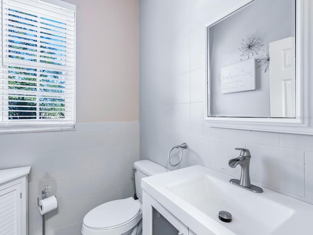 bathroom featuring vanity, toilet, and tile walls