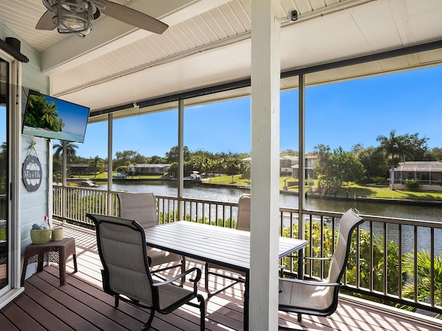 sunroom with ceiling fan and a water view