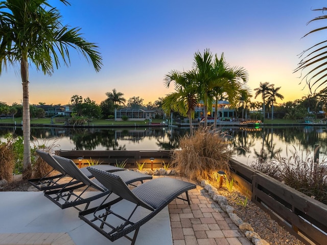 patio terrace at dusk featuring a water view