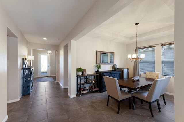 dining space with dark tile patterned floors and an inviting chandelier