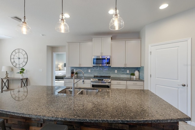 kitchen with decorative light fixtures, white cabinets, sink, and stainless steel appliances