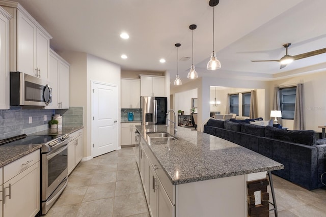 kitchen with stainless steel appliances, a large island with sink, backsplash, and sink