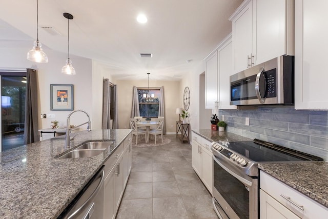 kitchen featuring white cabinetry, appliances with stainless steel finishes, dark stone counters, pendant lighting, and sink