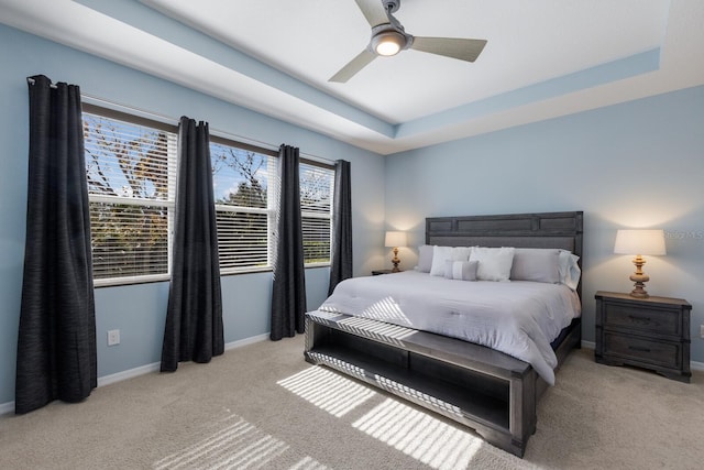 bedroom featuring ceiling fan, light colored carpet, and a raised ceiling