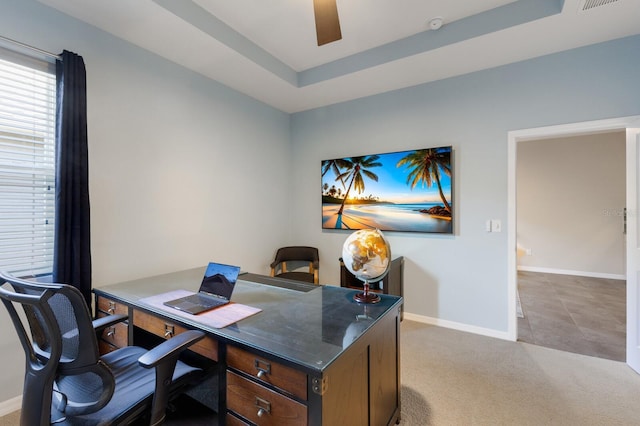 home office with a raised ceiling and light colored carpet