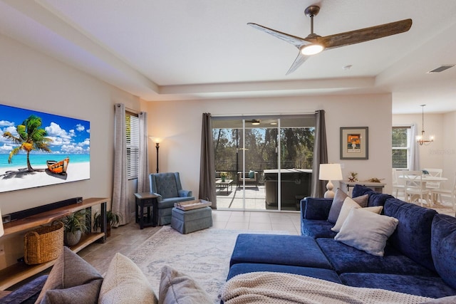 living room with ceiling fan, light tile patterned floors, and a tray ceiling