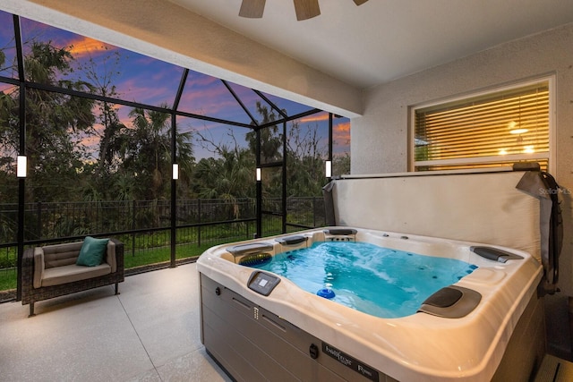 pool at dusk featuring ceiling fan, a hot tub, a patio area, and glass enclosure