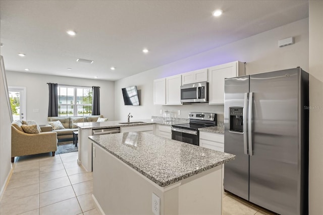 kitchen with kitchen peninsula, light tile patterned floors, stainless steel appliances, white cabinets, and light stone counters