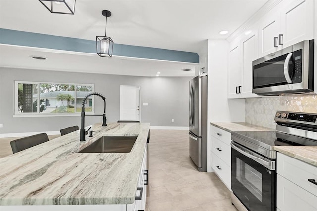 kitchen with light stone counters, stainless steel appliances, sink, decorative light fixtures, and white cabinetry