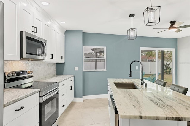 kitchen featuring appliances with stainless steel finishes, sink, pendant lighting, white cabinets, and an island with sink