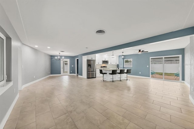 unfurnished living room with ceiling fan with notable chandelier