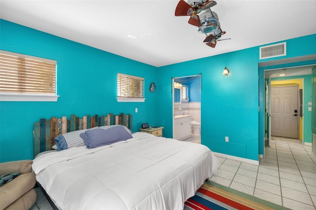 bedroom featuring ceiling fan, multiple windows, ensuite bath, and light tile patterned flooring