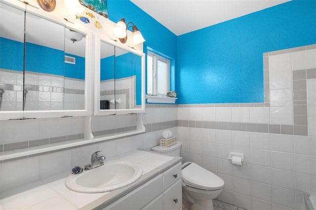 bathroom featuring toilet, tile walls, and vanity