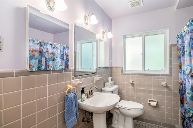 bathroom featuring toilet, tile patterned flooring, tile walls, a shower with curtain, and sink