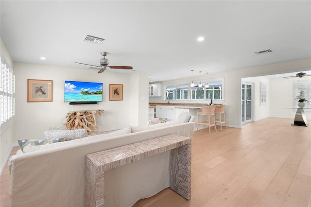 living room with light hardwood / wood-style flooring, ceiling fan, and sink