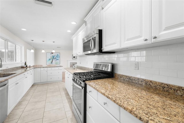 kitchen with sink, pendant lighting, decorative backsplash, white cabinets, and appliances with stainless steel finishes