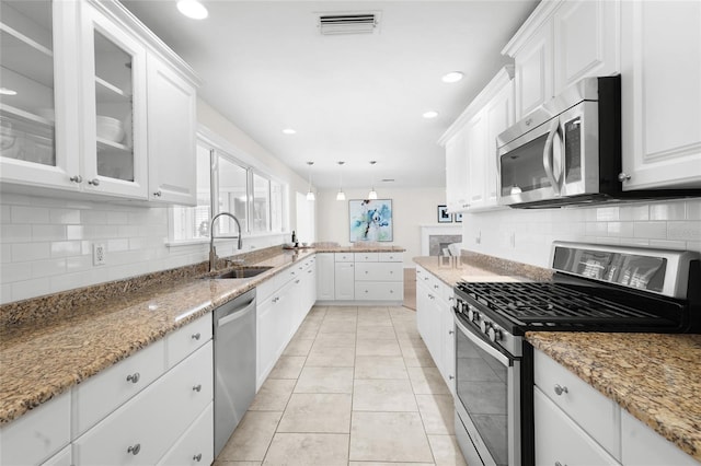 kitchen with decorative light fixtures, stainless steel appliances, white cabinetry, and sink