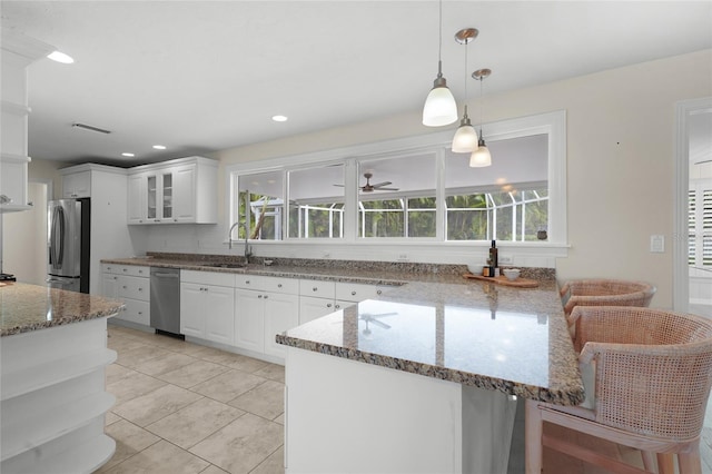 kitchen with white cabinets, appliances with stainless steel finishes, stone counters, and hanging light fixtures